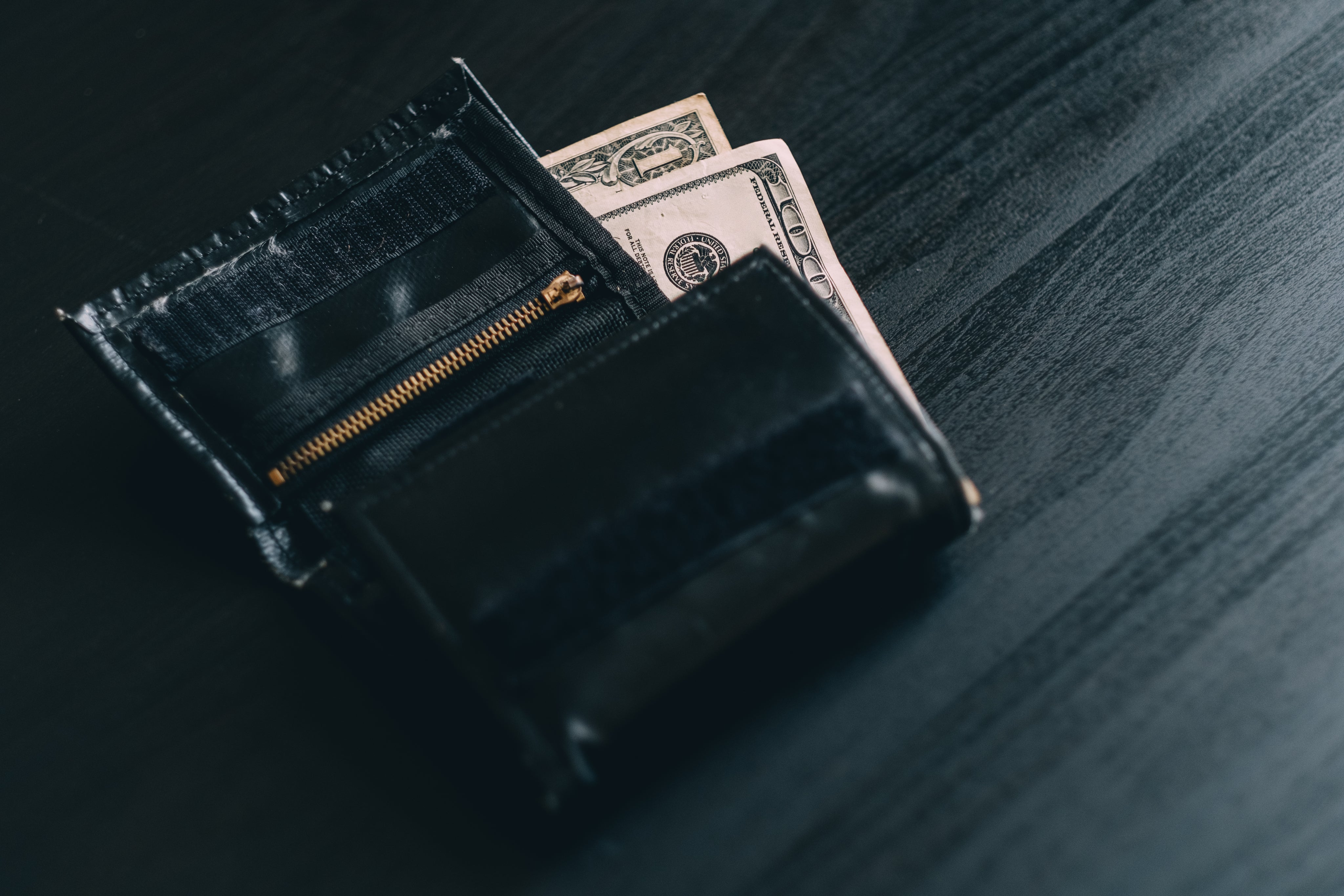 black-wallet-with-money-on-a-grey-wood-grain-surface